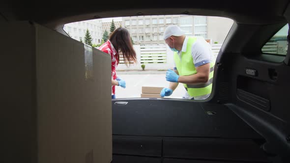 View From Car Trunk: Couriers, Man and Woman in Protective Masks, Gloves, Loading Parcels, Putting