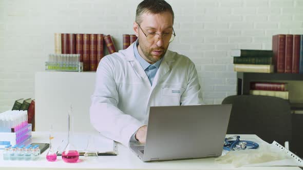 Front View of a d Doctor Writes a Report in His Office