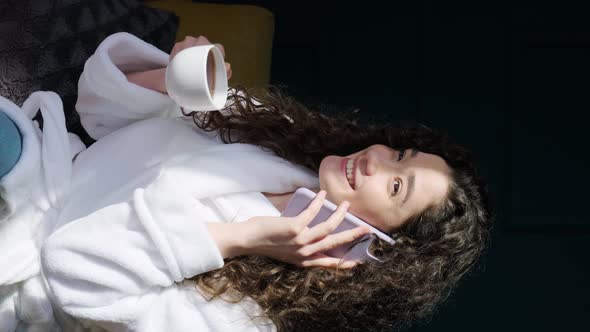 Curly Haired Girl Drinking a Tea at Home While is Talking on Phone After Having a Bath