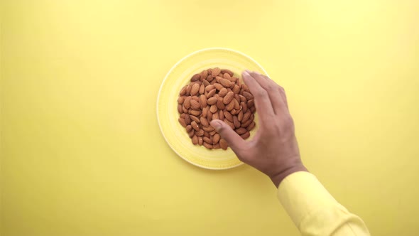 Top View of Hand Pick Almond Nut on Yellow Background