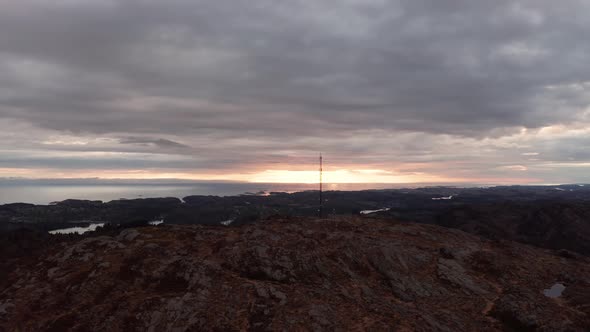 Tele-communication mast at Norwegian mountain peak in front of cloudy sunset at dawn - Late night as