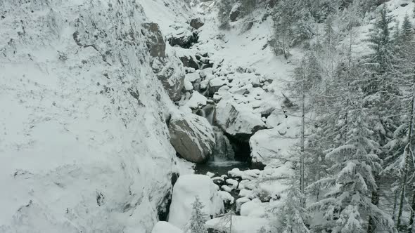 Flying towards small waterfalls in snow covered wilderness