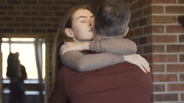 Portrait of Happy Beautiful Young Woman Hugging Man Indoors