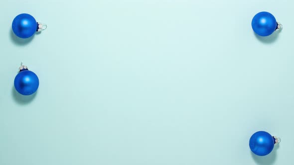 Blue christmas balls on blue background on left and right side.. Stop motion animation flat lay alt