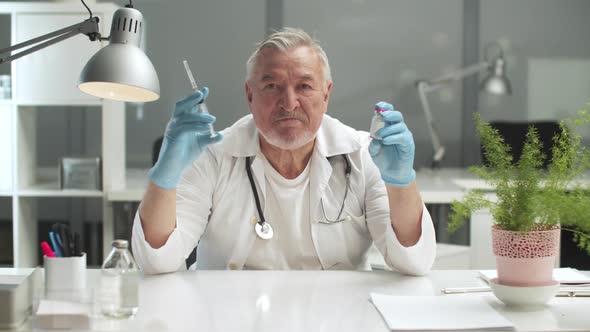 An Experienced Doctor Recommends Vaccination Holds a Syringe and a Bottle of Vaccine in His Hands