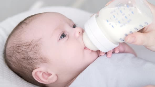 Loving Mother Feeding Her Little Boy Child with Milk Baby Bottle at Home Portrait Infant Baby Eating