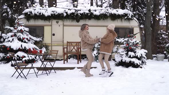 Mom and daughter are jumping in the snow holding hands