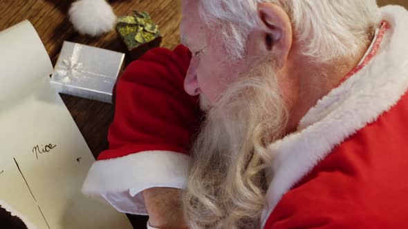 Santa claus sleeping at desk while writing a letter with a quill