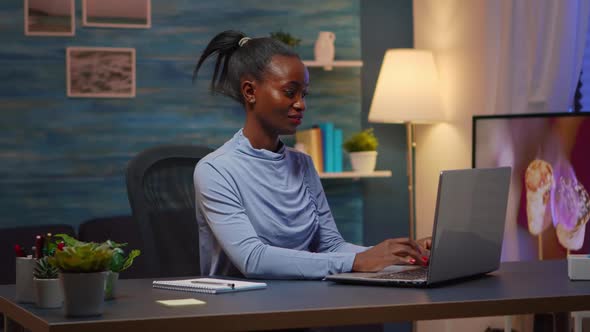 Black Woman Typing on Computer Smiling Late at Night