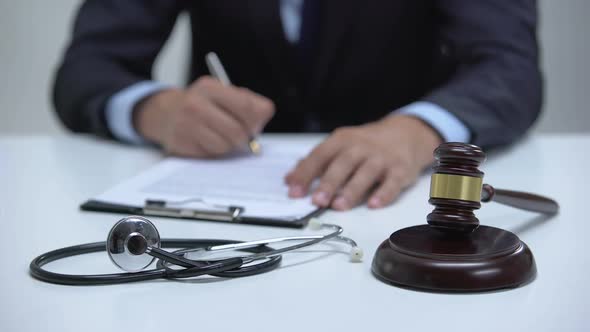 Judge Signing Arrest Warrant for Medical Error, Banging Gavel Near Stethoscope