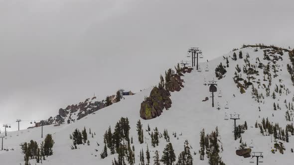 Ski mountain looking at skiing and snowboarding on snow with chairlift and clouds time lapse