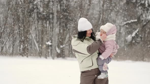 Mother with Kids Standing in Winter Forest on Snowy Weather