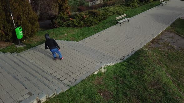 Aerial Drone Tracking Shot of a Young Adult Male Doing Parkour Free Running by Flipping Down Flights