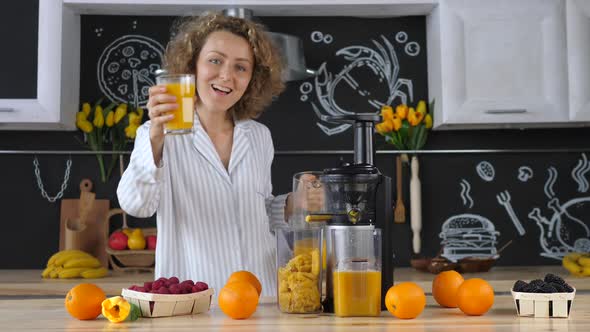 Beautiful Young Woman In Kitchen Squeezing Orange Juice With Juicer