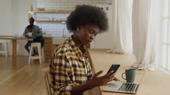 Woman using smartphone and laptop at home