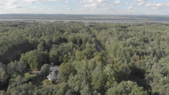 Aerial footage over a forested area with a home surrounded by a lake and mountains on a summer after