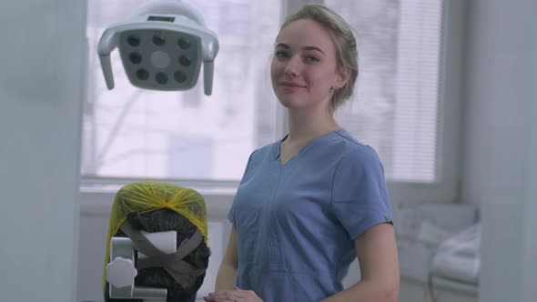 Pretty Smiling Female Dentist Assistant on Background of Dental Office