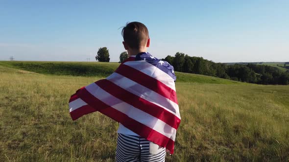 Boy Waving National USA Flag Outdoors Over Blue Sky at the River Bank