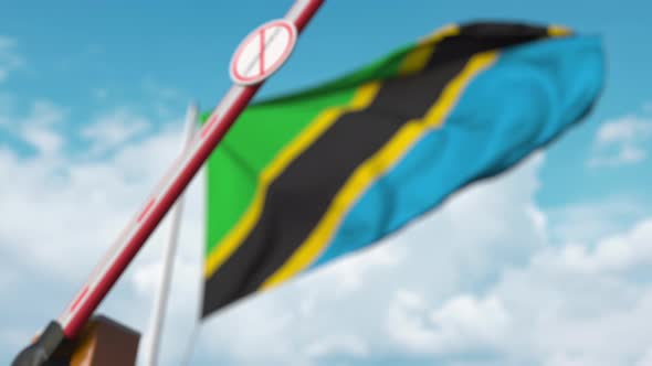 Closing Barrier with STOP CORONAVIRUS Sign at the Tanzanian Flag alt