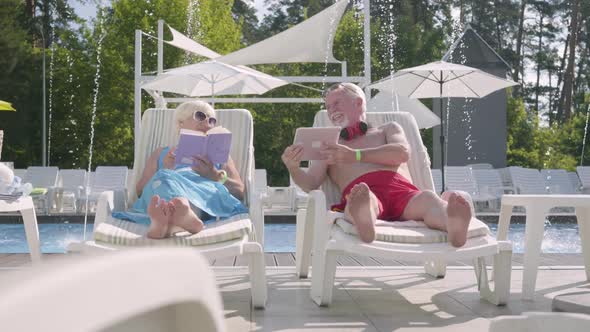 Adorable Positive Couple Lying on Sunbeds Near the Pool