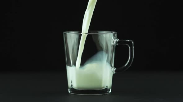 Milk Pouring Into Glass Mug Close Up Isolated on Black Background Slow Motion