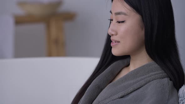 Camera Moves Down From Laughing Face of Asian Beautiful Woman to Laptop with Female Fingers Typing