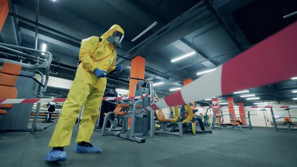 Sanitation Worker Sprays Antiseptic in a Gym.