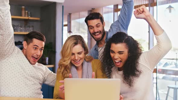 Smiling friends using laptop in caf������������