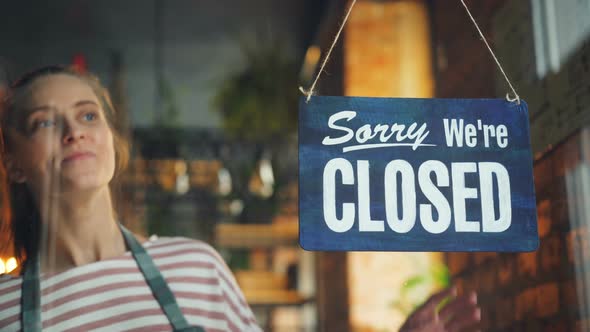 Cafe Manager Changing Closed To Open Sign on Window Smiling Looking Outside