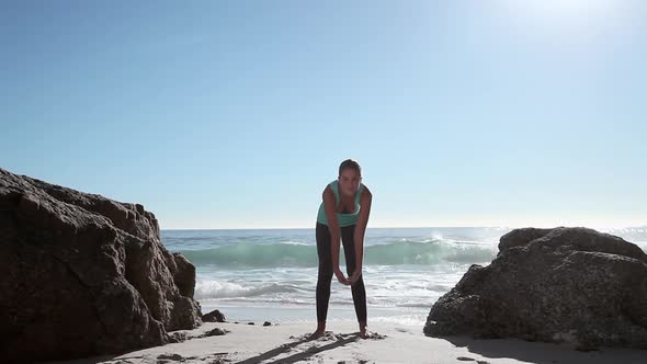 Young woman doing yoga on beach