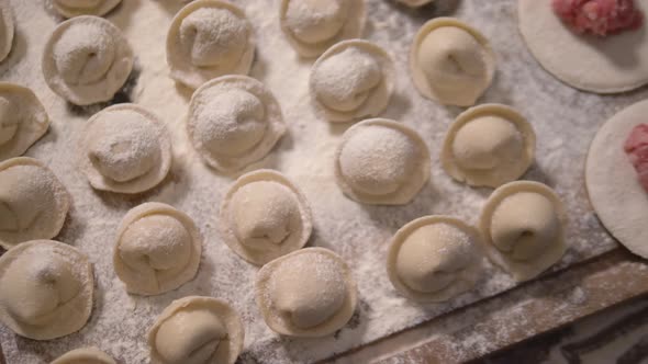 Rows of Prepared Dumplings Lie on a Wooden Board