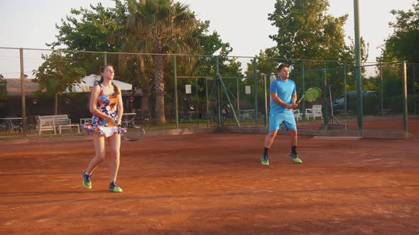 A Young Man and Woman on Tennis Training at Sunset