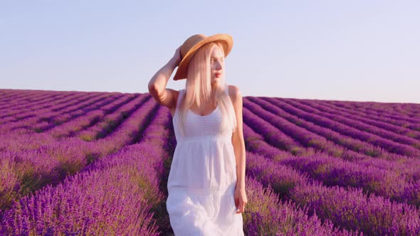 Young Woman in White Dress Walking Through a Lavender Field on Sunset