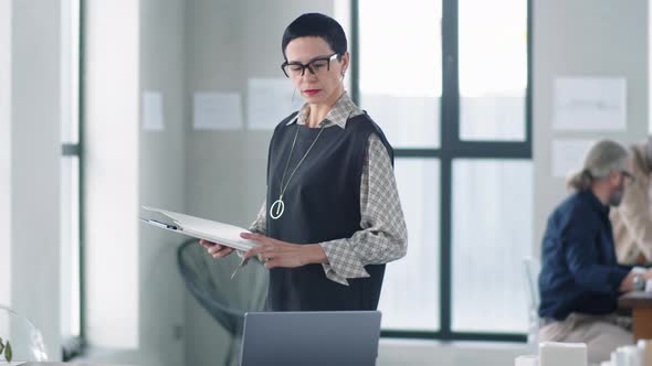 Elegant Business Lady Walking in Office and Checking Documents