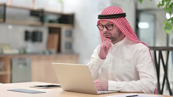 Thoughtful Young Arab Businessman Thinking and Working on Laptop in Office