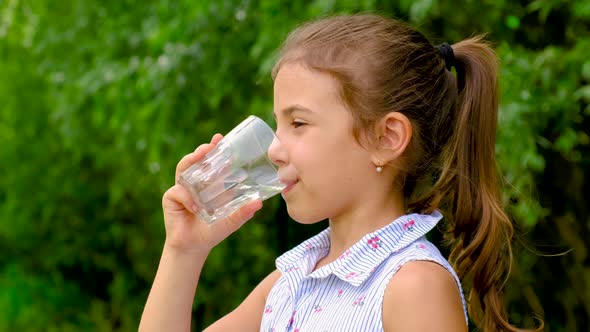 Child Girl Drinks Water From a Glass