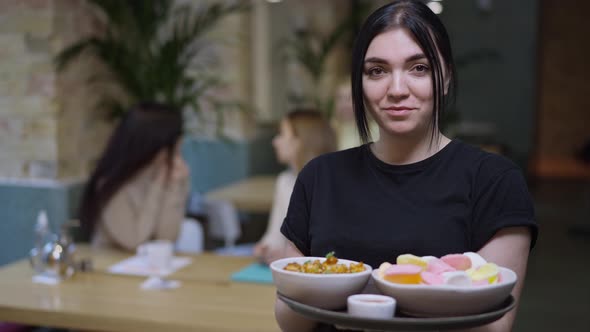 Portrait of Young Positive Caucasian Waitress Posing with Seafood on Tray Looking at Camera Smiling