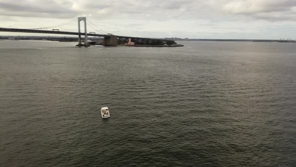 A low angle view of a single white boat anchored in the East River, near the Throgs Neck Bridge in N