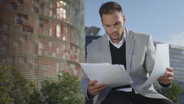 Businessman Looking at Papers on Street. Manager Celebrating Success Outside