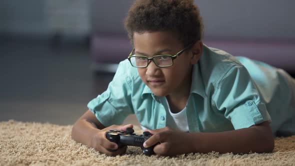 Afro-American Boy Absorbedly Playing on New Video Game Console Activity