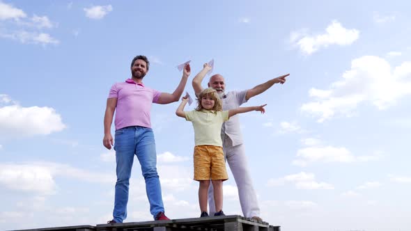 Happy Family of Boy Kid with Dad and Grandad Hold Paper Planes Pointing Fingers Skyhigh Aiming