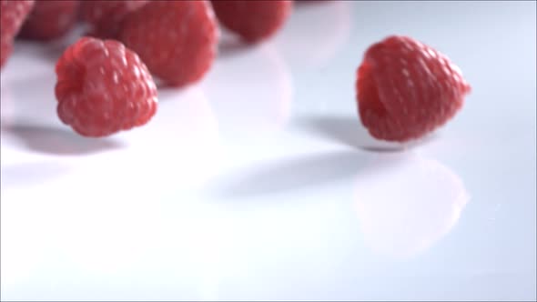 Raspberries Rolling Down on White Background