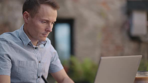 Smiling Man with Works From Home in His Kitchen Using a Laptop