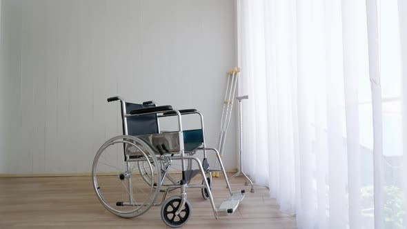 Empty modern wheelchair and walking stick or canes in hospital room.