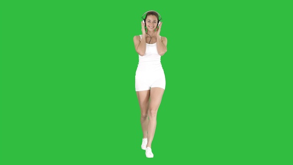 Sportswoman listening music in headphones on a Green Screen