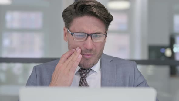 Close Up of Middle Aged Businessman with Laptop having Toothache