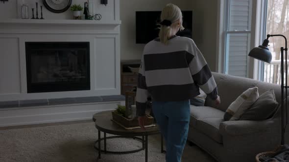 woman walking to the couch to lay down and scroll through tablet while drinking coffee in a nice hou