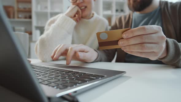 Close Up of Couple Sitting at Table and Doing Online Shopping on Laptop