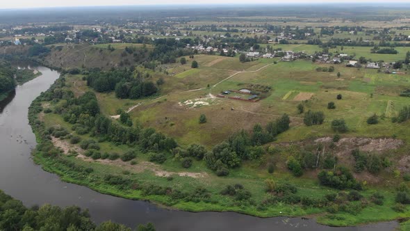 Aerial View of Meadow Bordering River with Small Village in Background