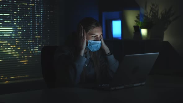 Scared Woman in Medical Mask Reading News About Coronavirus on Laptop in Darkness